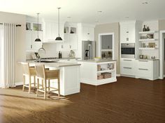 a large kitchen with white cabinets and wood flooring, along with an island in the middle