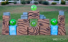 some cardboard boxes and green balloons in the grass