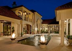 a large house with a fountain in front of it at night, lit up by candles