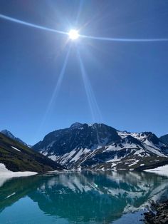 the sun shines brightly over a mountain lake