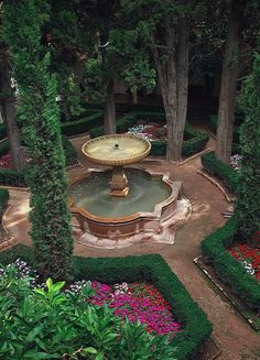 a fountain surrounded by lush green trees and flowers