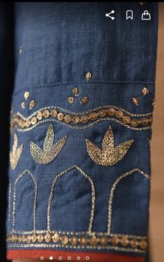 a close up of a person wearing a blue shirt with gold embroidered designs on it