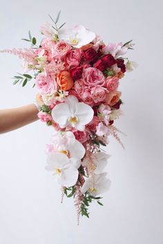 a person holding a bouquet of flowers in their hand with white and pink blooms on it