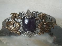 This beautiful silver plated filigree cuff bracelet has antique brass dragons, silver plated accents and an amethyst setting. Adjustable. Medieval Style Metal Jewelry For Fantasy Events, Medieval Style Silver Jewelry With Intricate Design, Fantasy Engraved Jewelry For Fantasy Events, Handmade Gothic Jewelry For Fantasy Events, Adjustable Silver Jewelry For Fantasy Events, Elegant Silver Jewelry For Fantasy Events, Medieval Handmade Cuff Bracelet As A Gift, Handmade Medieval Cuff Bracelet As Gift, Handmade Medieval Cuff Bracelet For Gifting