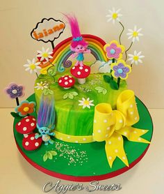 a birthday cake decorated with flowers, mushrooms and rainbows is on a green plate