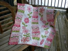 a pink and green quilt on a wooden bench