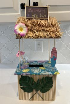 a tiki hut with a surfboard and flowers on the table next to it