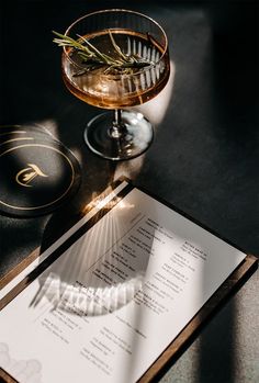 an empty menu sitting on top of a table next to a glass filled with wine