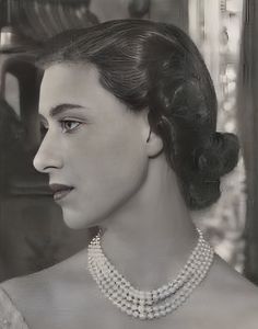 a black and white photo of a woman wearing a necklace with pearls on her neck