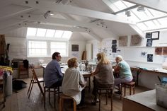 four people sitting at a table in an art studio