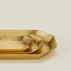 three gold trays on a white surface