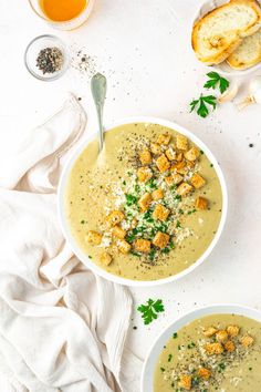 two bowls of soup with bread on the side