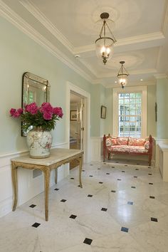 a vase with pink flowers sitting on top of a table in front of a couch