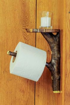 a toilet paper holder with a candle on it and a wooden wall in the background