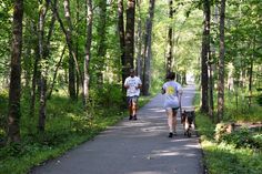 two people walking down a path in the woods