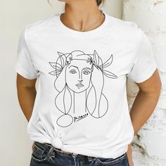 🖤FIND MORE TREASURES at MetisArtPrints * Explore our t-shirt collection! https://etsy.me/4bJMLv4 * Explore unique artworks! https://etsy.me/2Rw7KcO 🖤ABOUT This casual T-shirt features one of Picasso's famous drawings of women. It is the perfect gift for art lovers and artists alike. The unique design reflects Picasso's cubism style, adding an artistic touch to any wardrobe. 💯 HAPPINESS GUARANTEE * Your happiness is our priority. * If you have any issues with your order, let us know--we'll fix Artsy Short Sleeve T-shirt With Artwork, Artistic Short Sleeve Top With Artwork, White T-shirt With Artwork For Summer, Artistic Crew Neck Shirt For Summer, Artsy Short Sleeve Tops With Artwork, Cotton Artwork T-shirt With Crew Neck, Graphic Cotton Tee With Artwork, Cotton Graphic Tee With Artwork, Artistic White Tops With Custom Artwork