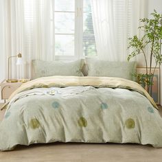 a bed in a bedroom with white curtains and green polka dot bedspread on it