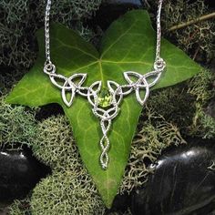 "I've designed this long, statement Celtic inspired necklace entirely in sterling silver featuring a center, faceted 10x8mm peridot gemstone! The frame, or centering, of the pendant is made with Celtic Trinity Knots and sterling wire work braids down the center to add the balancing touches to the piece. It comes with a sterling box chain which is soldered to each end of the pendant. This piece is 18\" in length, including the chain, and the pendant, itself, is approximately 3 inches, in height, Lime Green Peridot Jewelry For Wedding, Silver Peridot Jewelry For Anniversary, Elegant Lime Green Sterling Silver Jewelry, Sterling Silver Lime Green Gemstone Jewelry, Lime Green Sterling Silver Gemstone Jewelry, Lime Green Sterling Silver Birthstone Jewelry, Lime Green Gemstone Jewelry In Sterling Silver, Silver Peridot Jewelry As Gift, May Birthstone Jewelry In Silver With Peridot