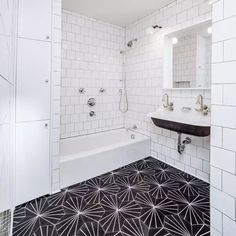 a bathroom with black and white tiles on the floor, sink, mirror and bathtub