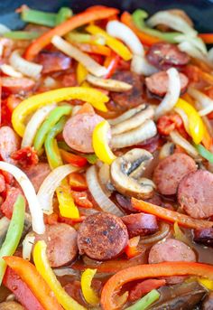 a pan filled with sausage, peppers and mushrooms