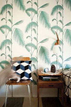 a chair and table in front of a wall with palm leaves on it