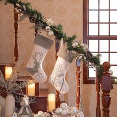 christmas stockings hanging from a banister with candles and decorations