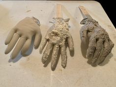 three gloves and one pair of scissors laying on a table with mud all over them