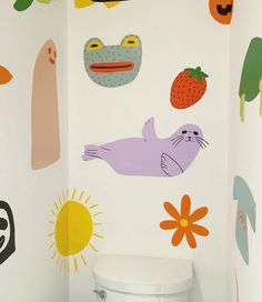 a white toilet sitting in a bathroom next to a wall with cartoon animals on it