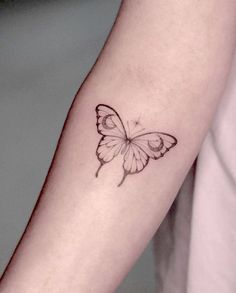 a small butterfly tattoo on the left forearm and arm, it is black and white