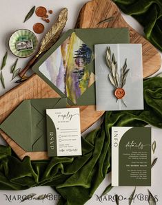 the wedding stationery is laid out on top of some green leaves and other items