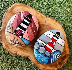 two painted rocks sitting on top of a wooden stump in the grass next to each other