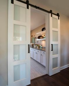 an open door leading to a kitchen with white cabinets and drawers in the back ground