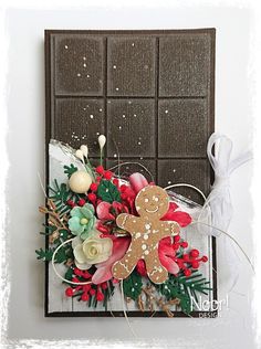 a christmas card with a gingerbread cookie and holly wreath on it, next to a chocolate bar