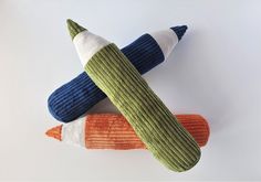 two knitted objects are laying on top of each other, one is green and the other is orange