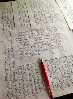 several sheets of paper with cursive writing on them and a red pen resting on top