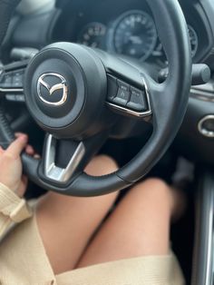 a woman is sitting in the driver's seat of a car with her hands on the steering wheel