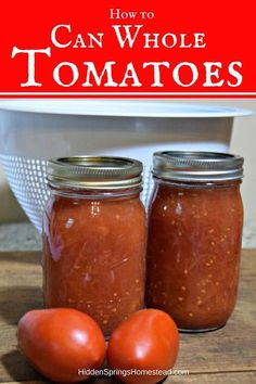 two jars filled with tomato sauce sitting on top of a wooden table next to tomatoes