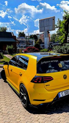 a yellow vw golf gtr parked on the side of a road in front of a building