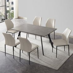 a dining table with six chairs and a rug on the floor in an empty room