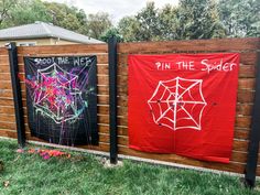 two red and black banners with spider webs on them in front of a fence