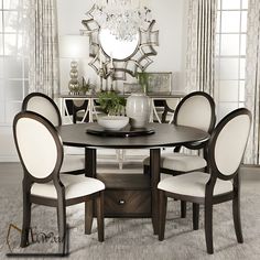 a dining room table with white chairs and a large mirror on the wall above it