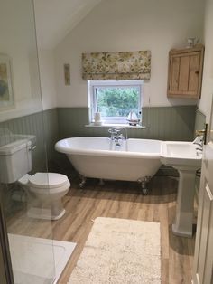 a white bath tub sitting inside of a bathroom next to a toilet under a window