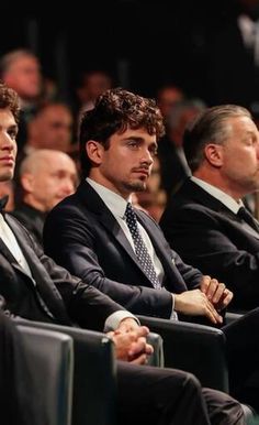 three men in suits and ties sitting next to each other at a convention or conference