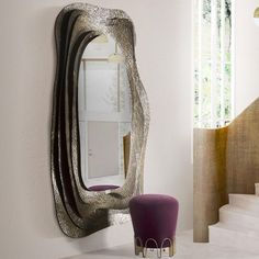 a mirror sitting on top of a wall next to a purple chair