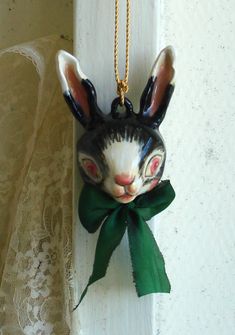 a ceramic rabbit head hanging on the side of a wall with a green bow around it's neck