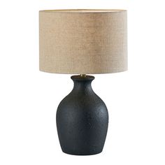 a black table lamp with a beige shade on the base and a white linen lampshade