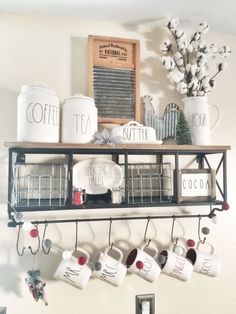 coffee mugs are hanging on the wall above a shelf with cups and other items