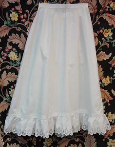 This is a sweet antique Edwardian petticoat. It is white cotton and has an eyelet ruffle at the bottom. It has a placket and pearl button at the waist. I have shown one little hole in the ruffle and there is a little wear here and there on the ruffle but very little and nothing distracting. I have also shown one pinhole near the ruffle. It is a petite size with a 22" waist and the length is 28". It has been freshly washed and ironed and has no spots. I combine shipping and am happy to provide a shipping quote to international shoppers. Thanks for visiting... Daywear Ruffled Petticoat, White Regency Style Petticoat With Ruffles, White Cotton Petticoat With Attached Cancan, Regency Style Ruffled Petticoat For Daywear, Elegant Cotton Petticoat For Summer, Victorian White Ruffled Petticoat, Victorian White Petticoat With Ruffles, Daywear Cotton Petticoat With Lace Trim, White Petticoat For Daywear In Spring