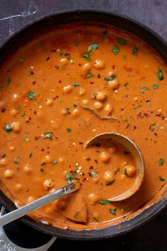 a pot filled with beans and garbanzo sauce on top of a wooden spoon