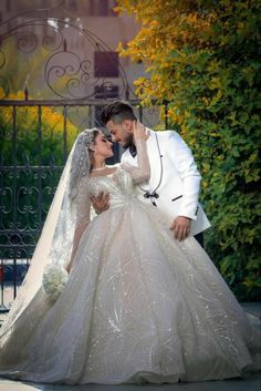 a bride and groom kissing in front of an iron gate